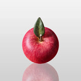 Fiberglass red apple sculpture is displayed on the dark marble table indoors.