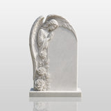 White marble tombstone with side praying angel stands on the green burial lawn.