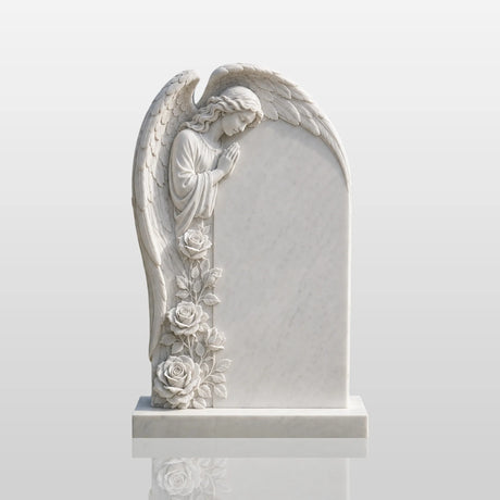 White marble tombstone with side praying angel stands on the green burial lawn.