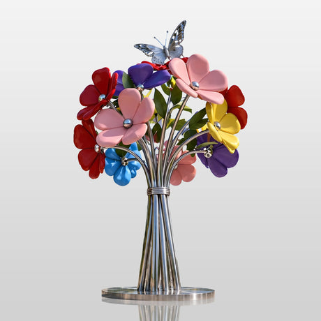 A stainless steel flower bouquet sculpture with a butterfly sits in a plaza in front of modern office buildings.