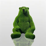 Green fiberglass bear statue sits on a concrete plinth outside the modern building.