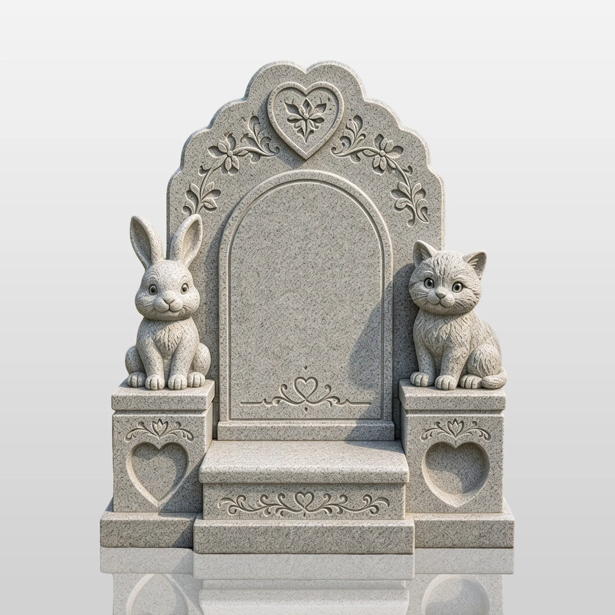 A gray granite animal tombstone with rabbit and cat statues sits in a cemetery garden.