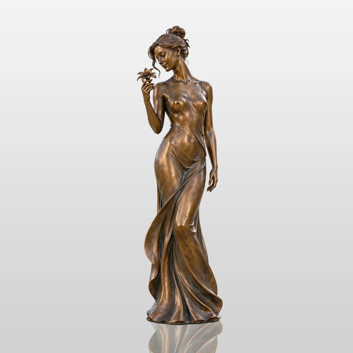 Bronze lady statue with a flower stands on a paved patio beside lush greenery.