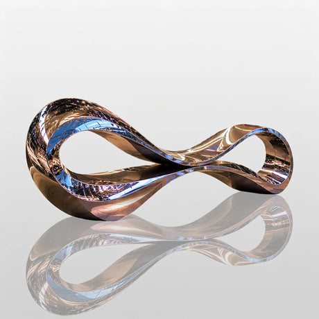 Mirror polished abstract stainless steel bench sculpture rests on tiled mall walkway beside flower planters and glowing light strips at night.