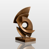A modern bronze sculpture sits on a display stand inside a home interior.