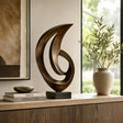 A bronze abstract sculpture stands on a wooden cabinet beside a door.