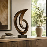 A bronze abstract sculpture stands on a wooden cabinet beside a door.
