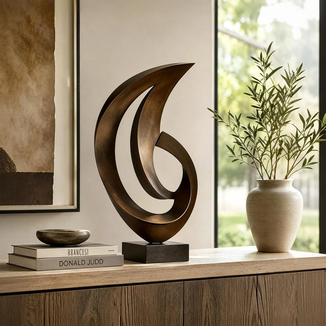 A bronze abstract sculpture stands on a wooden cabinet beside a door.