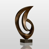 A bronze abstract sculpture stands on a wooden cabinet beside a door.
