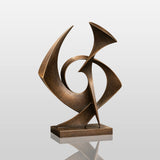 A bronze sculpture with intertwined shapes rests on a dark stone base inside a room.