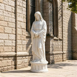 White marble Jesus statue stands on stone pavement beside a church building.