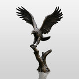 Large bronze eagle statue stands on grass beside a curved backyard swimming pool.