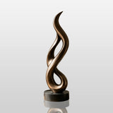 A tall twisted bronze sculpture stands in a bright modern living room beside a fireplace.