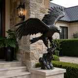 Dark bronze eagle statue perches on a stone pedestal near a home entrance.