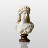 Marble veiled female bust sits on a marble table inside columned classical gallery hall.