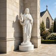 Marble Sacred Heart of Jesus statue stands near a stone church.