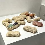 A group of abstract marble sculptures shaped like peanuts is displayed on a white pedestal.