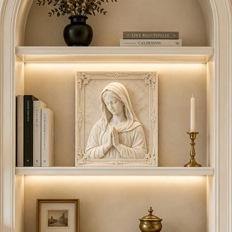 Marble Virgin Mary wall relief sculpture displayed on lit built in shelving indoors.