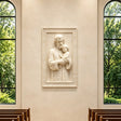 Marble relief of Saint Joseph and child Jesus hangs inside bright chapel.