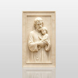 Marble relief of Saint Joseph and child Jesus hangs inside bright chapel.