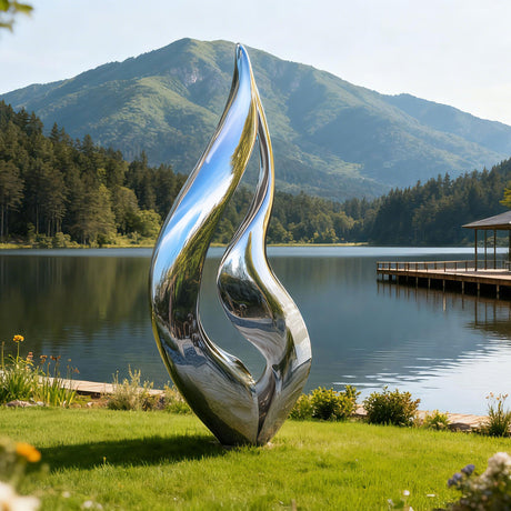 modern stainless steel flame sculpture beside a lake in a garden
