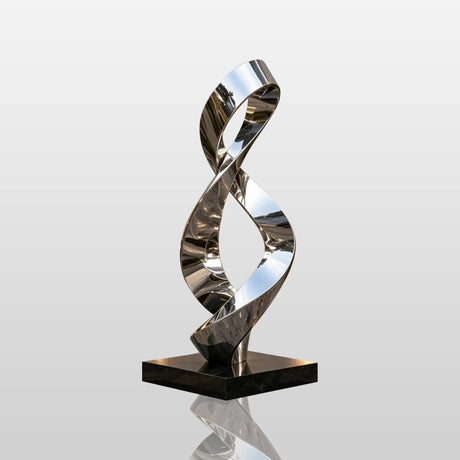A shiny stainless steel sculpture with infinity loop design stands on paved ground outside a building.