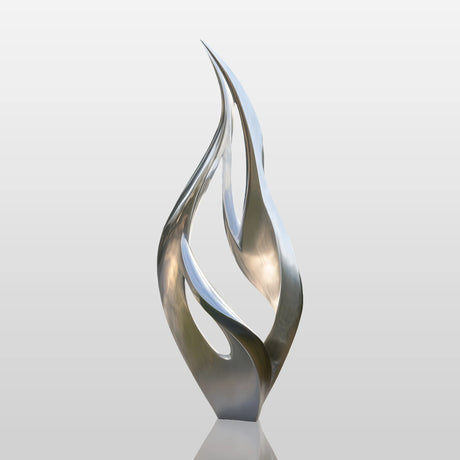 Stainless steel flame-shaped sculpture displayed in modern courtyard.