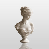 White marble female bust statue sits on a dark marble table in a refined indoor room.