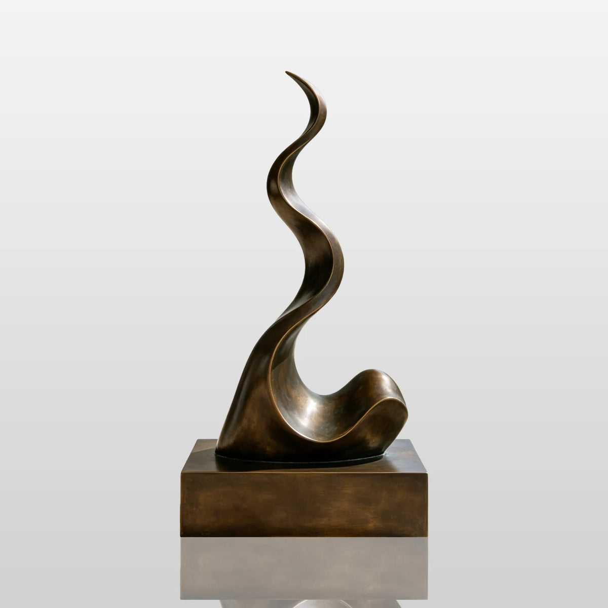 A wavy abstract bronze sculpture stands on the terrace of a modern home with glass railing.