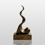 A wavy abstract bronze sculpture stands on the terrace of a modern home with glass railing.