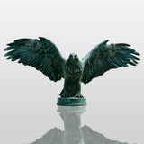 Patina bronze eagle statue perches on the stone column overlooking distant city skyline.