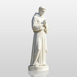 A Saint Francis of Assisi statue in white marble stands on the base beside a house.