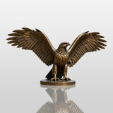 A large bronze eagle statue stands on a pedestal overlooking a valley and town.