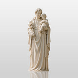 Marble saint Joseph statue holding infant Jesus stands on the stone courtyard.