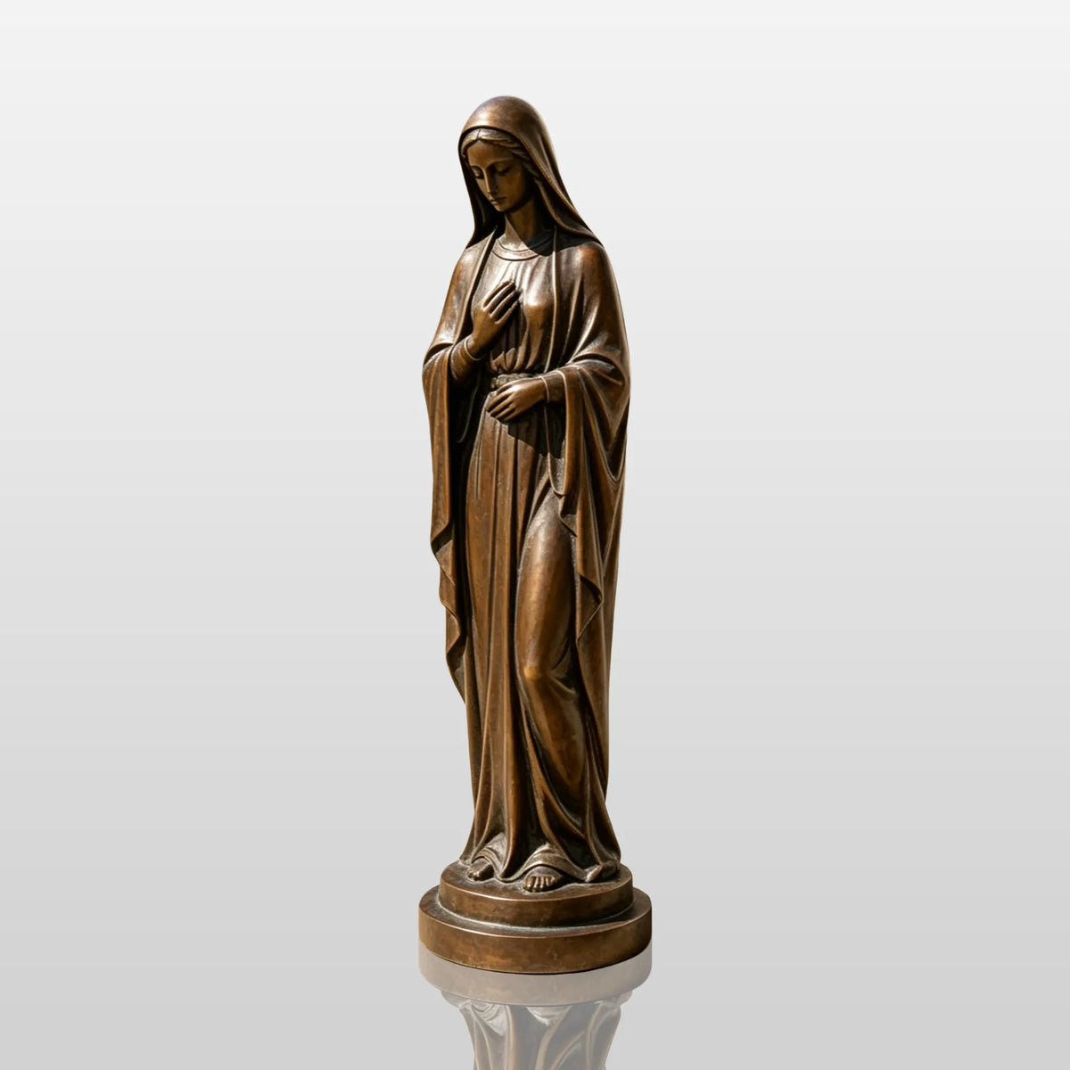 A bronze Virgin Mary statue stands on the paving inside an arched church courtyard.