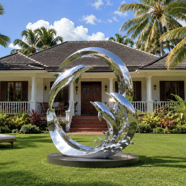 Circular ring dolphin stainless steel sculpture stands on the green front lawn under bright blue sky.