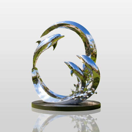 Circular ring dolphin stainless steel sculpture stands on the green front lawn under bright blue sky.