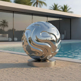 Polished stainless steel abstract sphere sculpture beside a pool at a modern residence
