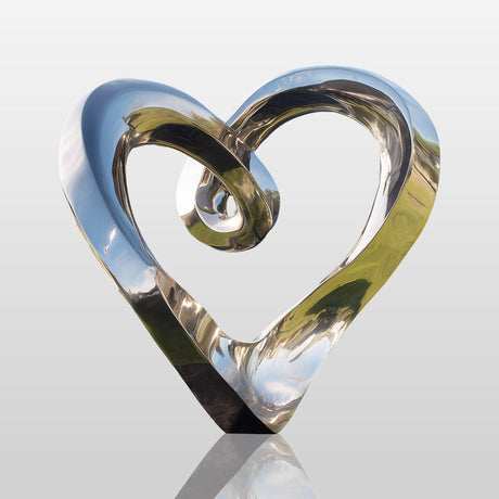 Stainless steel heart sculpture with flowing modern design in a luxury outdoor space.