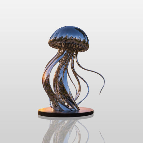 Shiny stainless steel jellyfish statue sits on a coastal flower bed with ocean sunset.