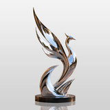 Mirror polished abstract phoenix stainless steel sculpture sits on the patio under warm dusk light.