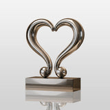 Polished stainless steel heart tabletop sculpture sits inside a display cabinet.