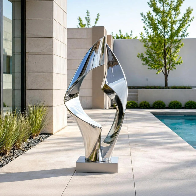 Polished loop stainless steel sculpture stands beside a swimming pool.