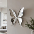 The stainless steel butterfly wall sculpture hangs on a light interior wall of a home.