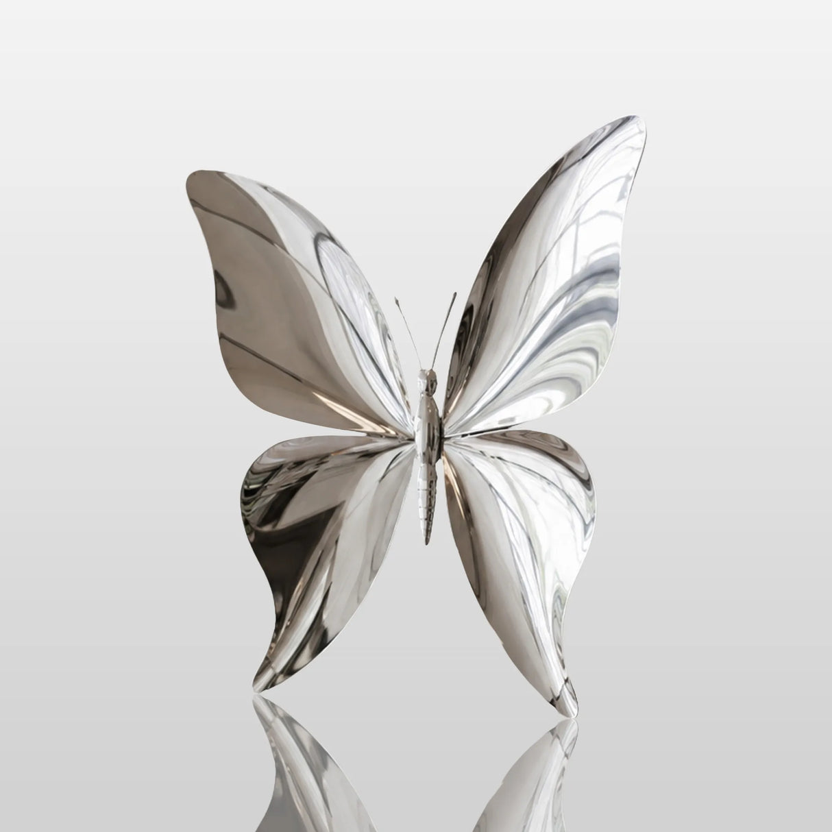 The stainless steel butterfly wall sculpture hangs on a light interior wall of a home.