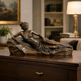Bronze reclining woman sculpture rests on the wooden cabinet inside a classic home.