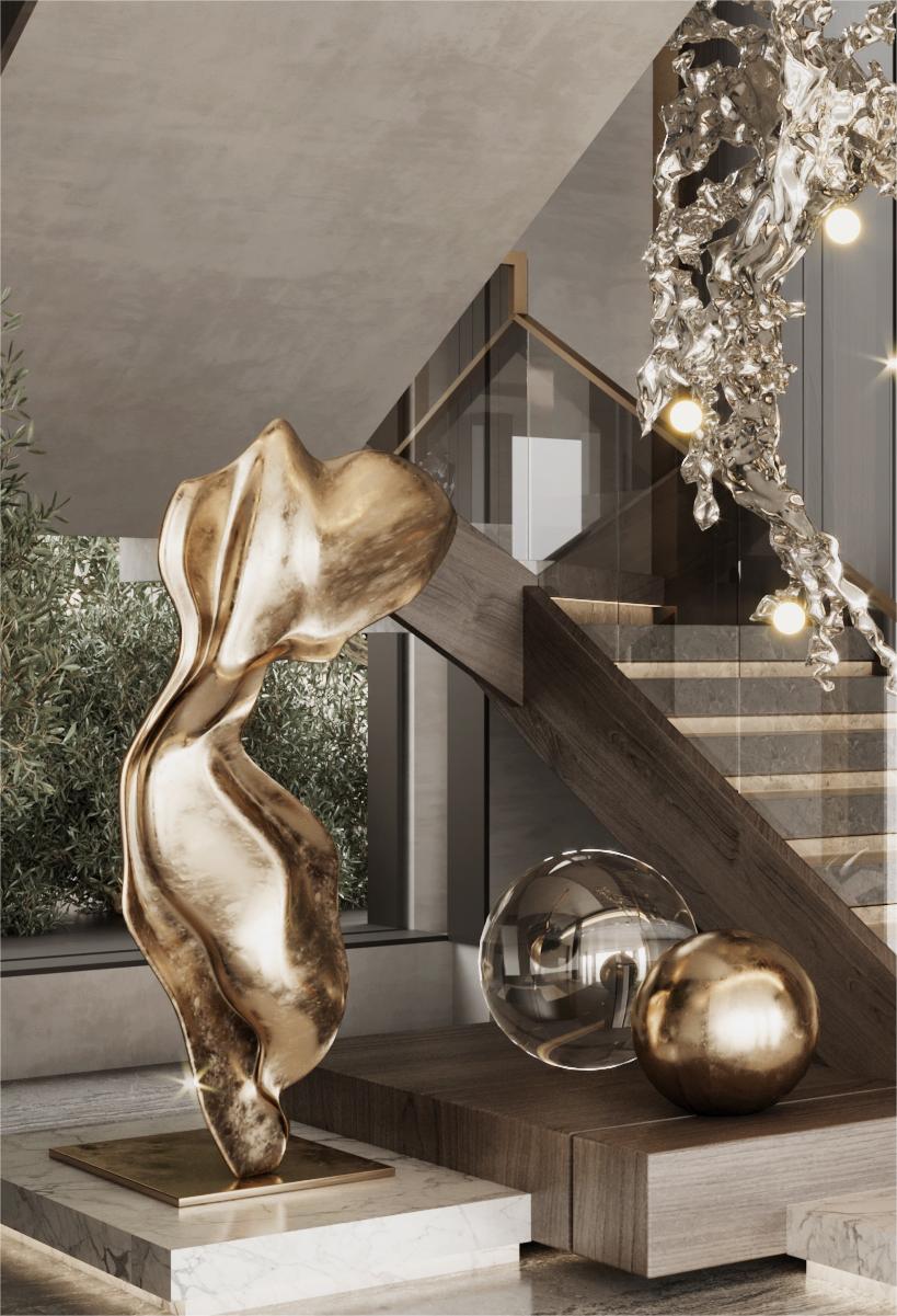 A fluid, abstract stainless steel sculpture accompanied by two spherical decorative sculptures in silver and gold