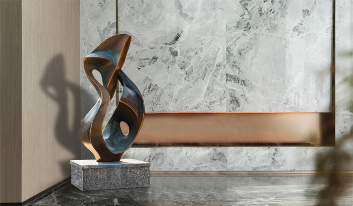 A modern abstract sculpture, made of bronze with hints of patina, features smooth surfaces