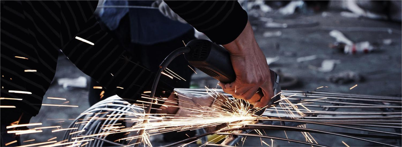 A person using an angle grinder to cut through metal sculpture