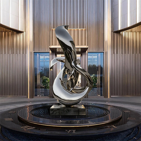 A sleek, modern sculpture of an abstract dolphin figure, crafted from polished stainless steel, stands in the center of an courtyard.